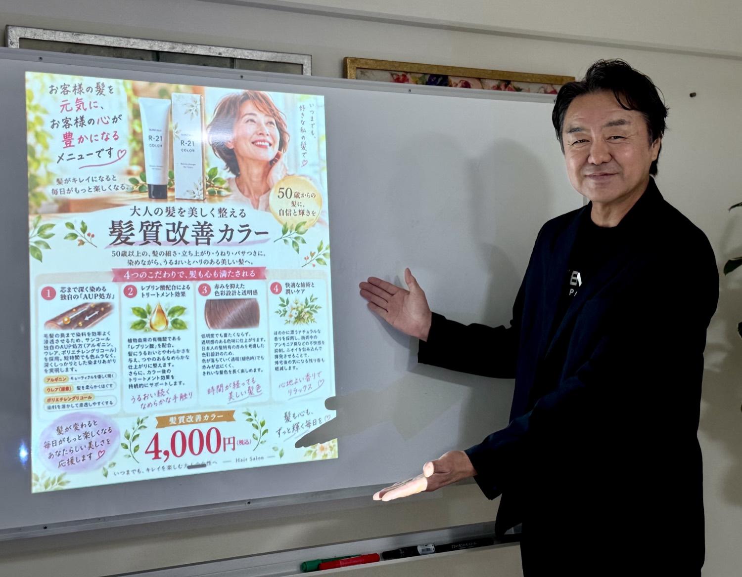 Mさんが、髪質改善カラーのサロンチラシの前でポーズしている