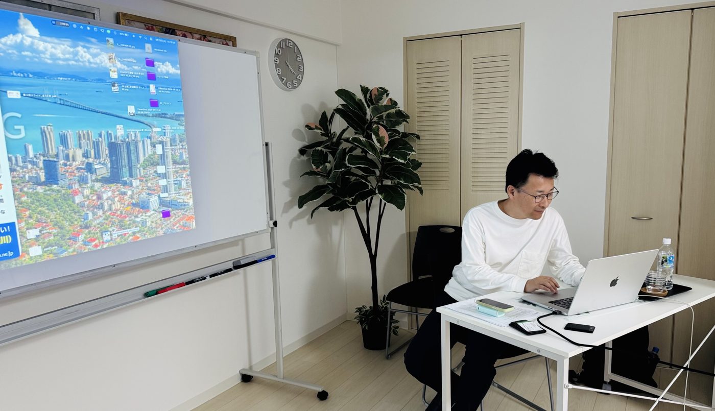 スクリーンの横でノートパソコンを操作する伊藤ゆきひろ