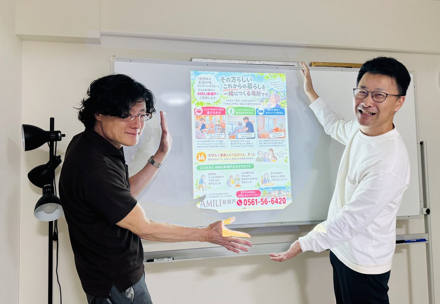 完成した高齢者向け住宅のチラシの前で並ぶ参加者と講師